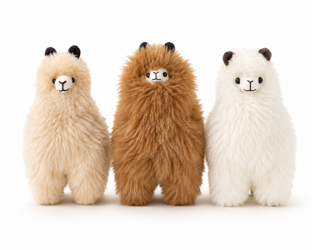 Three plush alpacas in beige, brown, and white on a white background